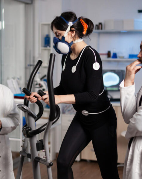 athlete-woman-with-mask-running-gym-bycle-trainning-body-endurance-while-researcher-doctor-measuring-heart-rate-monitoring-egk-data-laboratory-sportwoman-with-medical-electrodes-it
